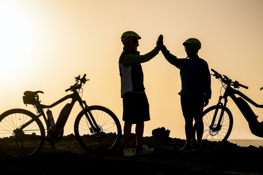 couple of two seniors and mature people together at the sunset with their bikes giving five