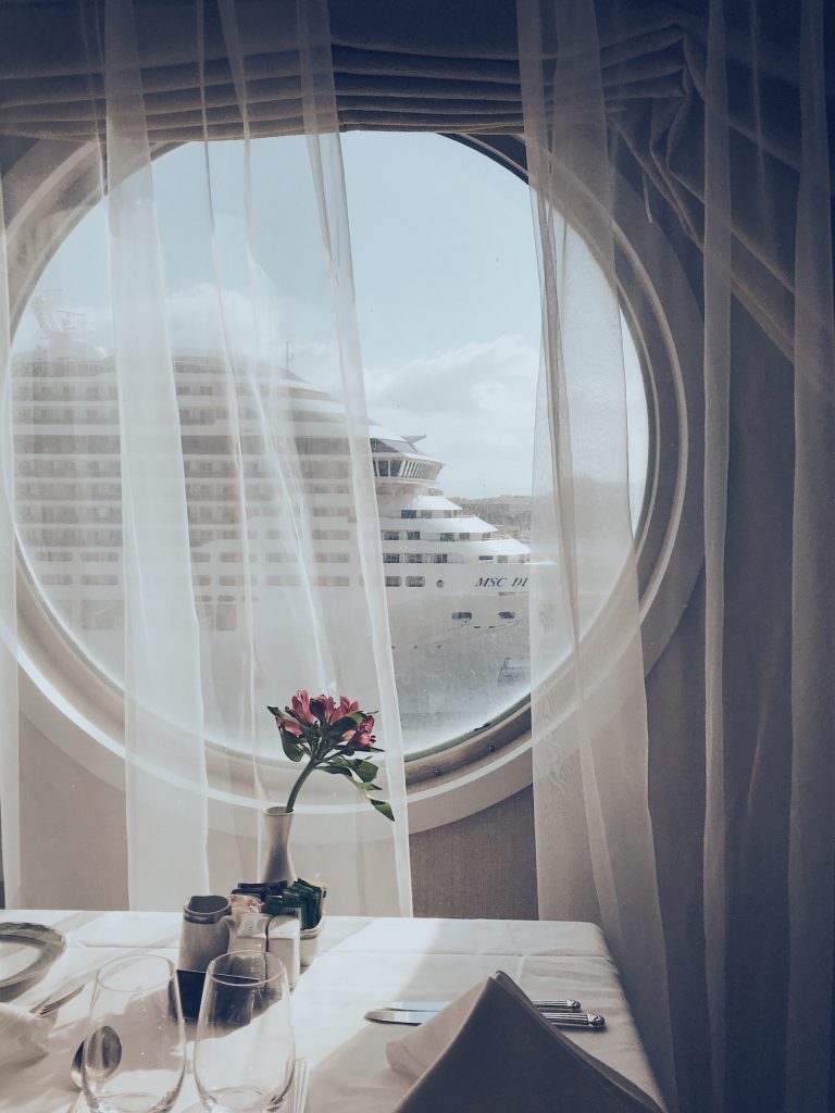 Dining table on a cruise ship with a view of a cruise ship from the window