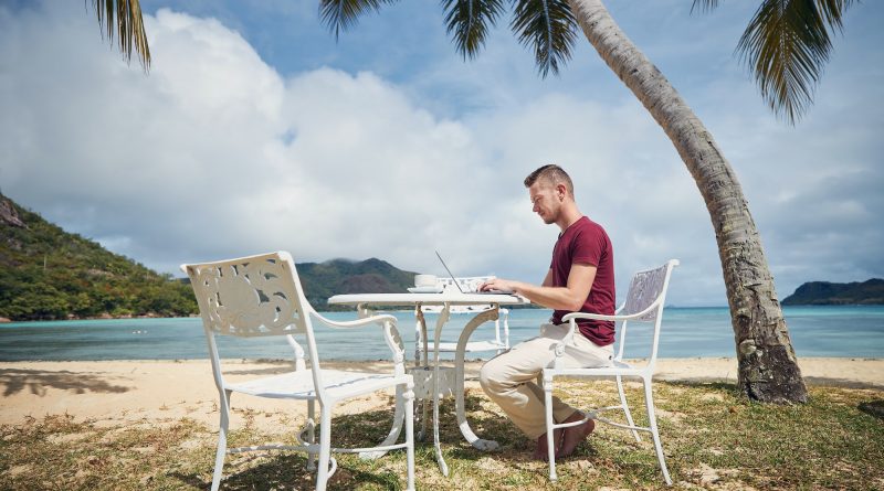 Man working on laptop on beach