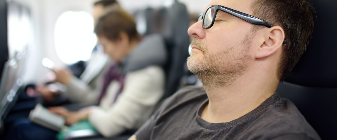 Mature man sleeping while traveling by an airplane