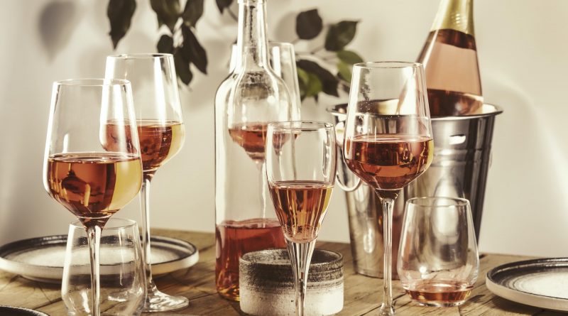 Rose wine glasses and bottles on table served for festive dinner party