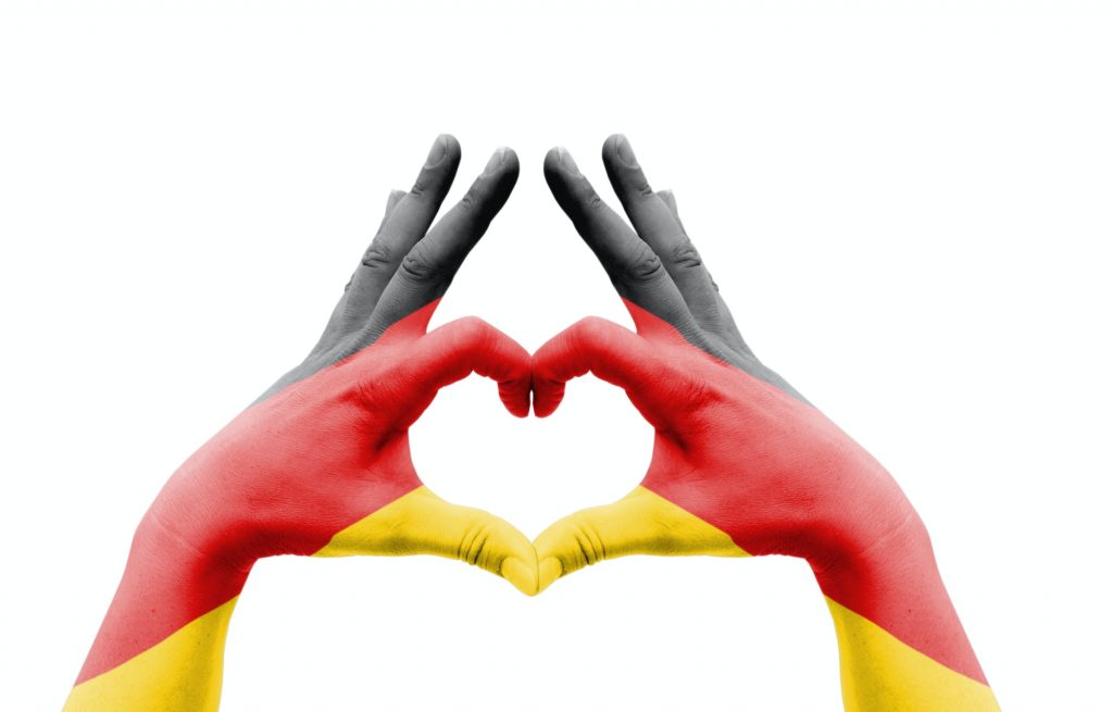 Two hands of a person painted with the flag of Germany forming a heart