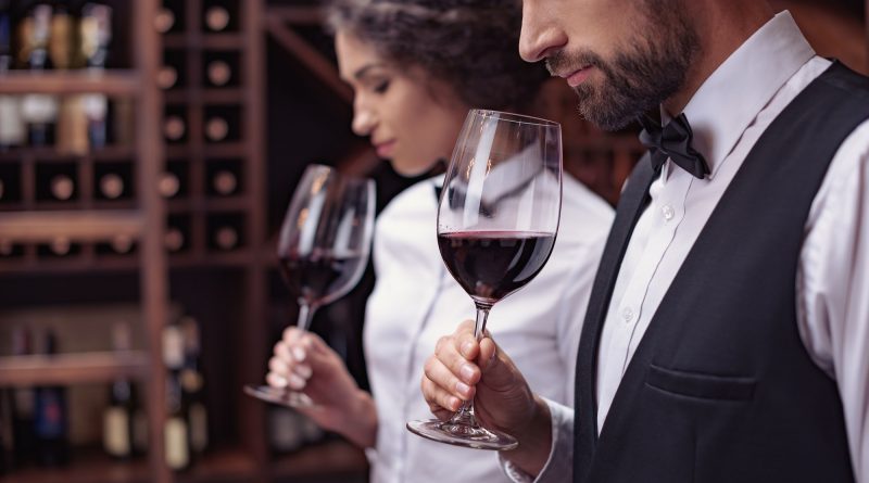 Two sommeliers, male and female tasting red wine in cellar