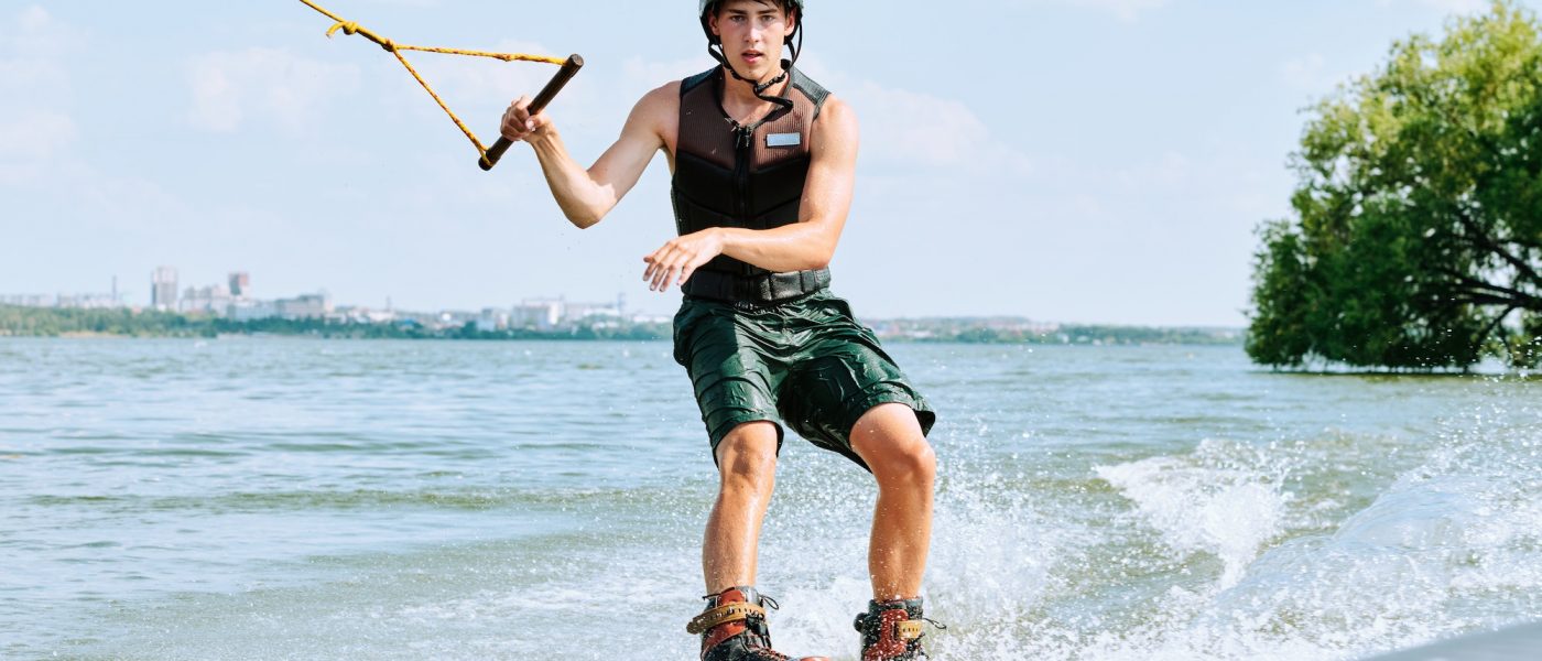 Young sportsman in shorts, safety jacket and helmet holding by handle with rope