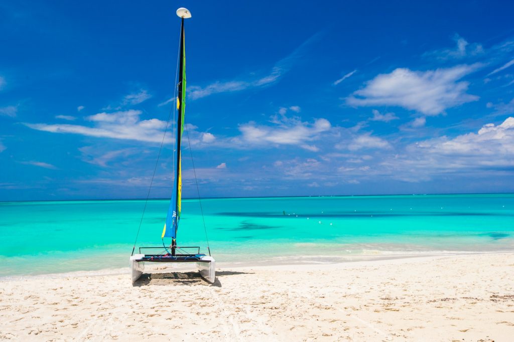 Catamaran with colorful sail on caribbean beach