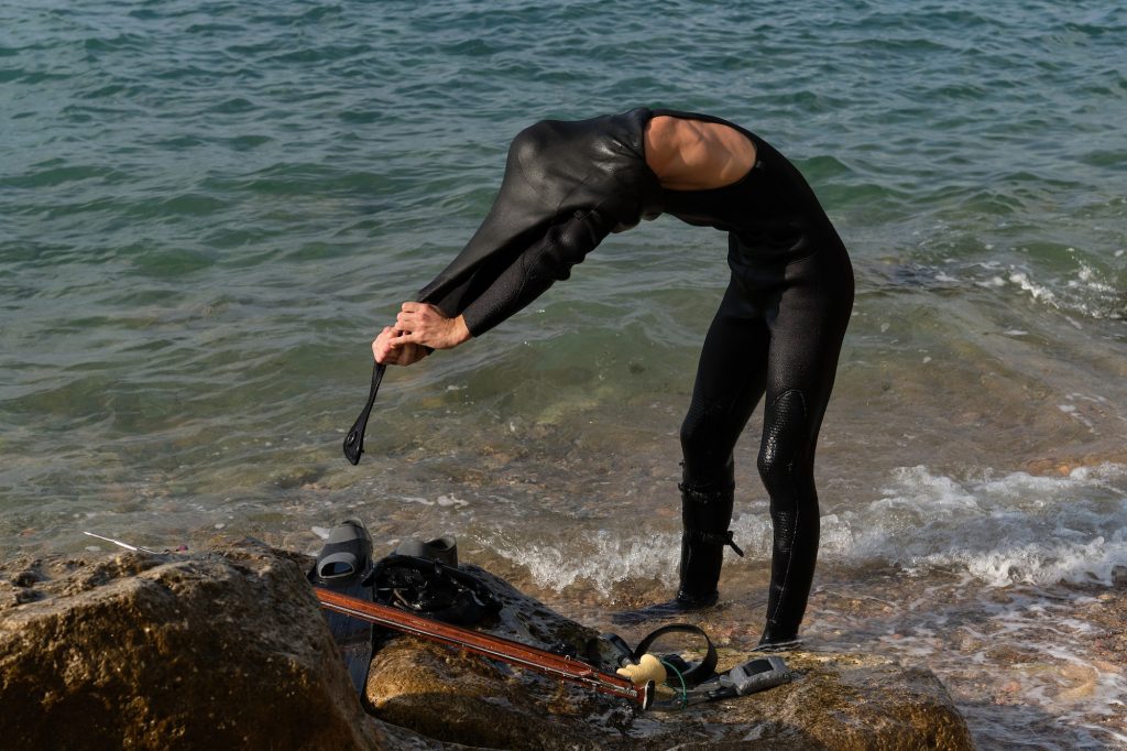 Diver taking off wetsuit after spearfishing