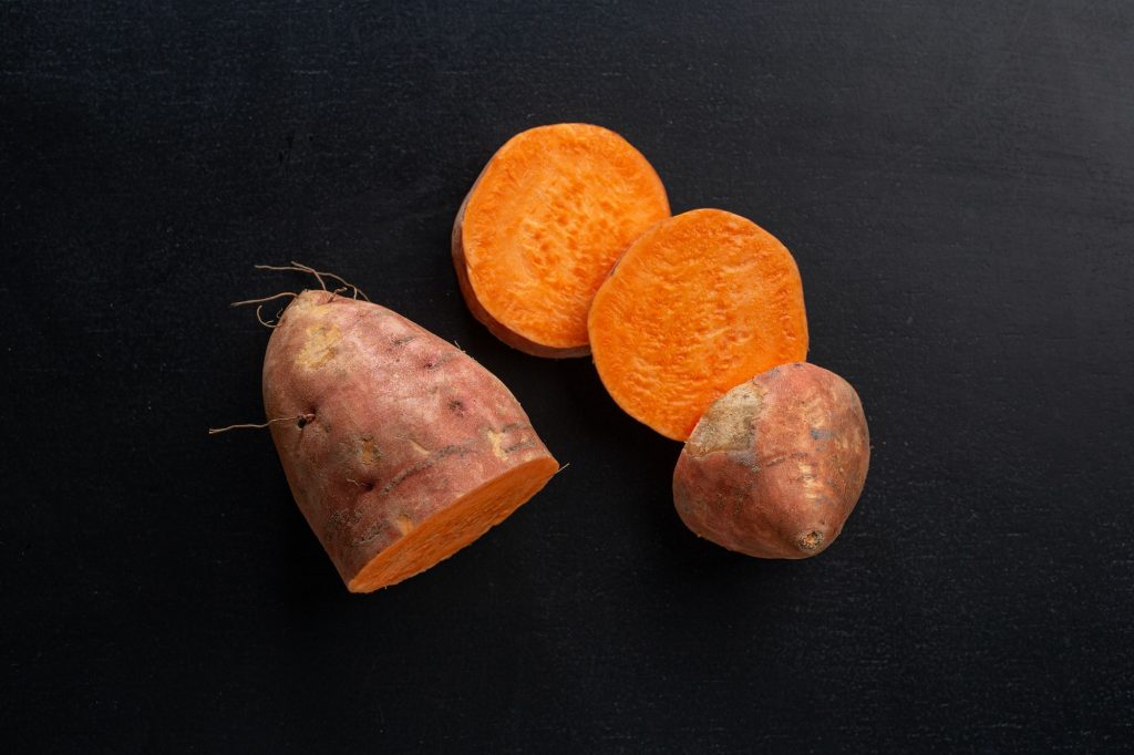 Raw sweet potato on dark background