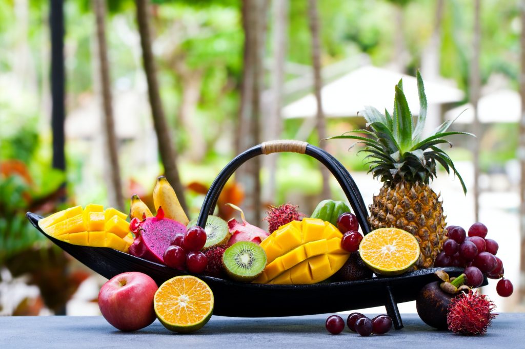 Tropical Fruits Assortment in Wooden Boat. Outdoor Tropical Background. Copy Space.