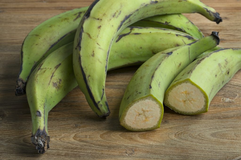 Whole and half green unripe bananas