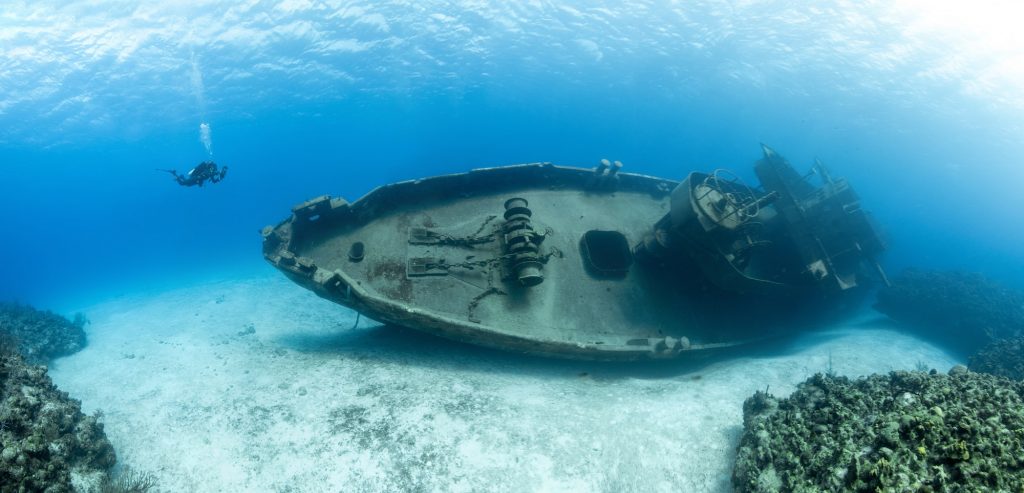 Scuba divers examining the famous USS Kittiwake submarine wreck in the Grand Cayman Islands
