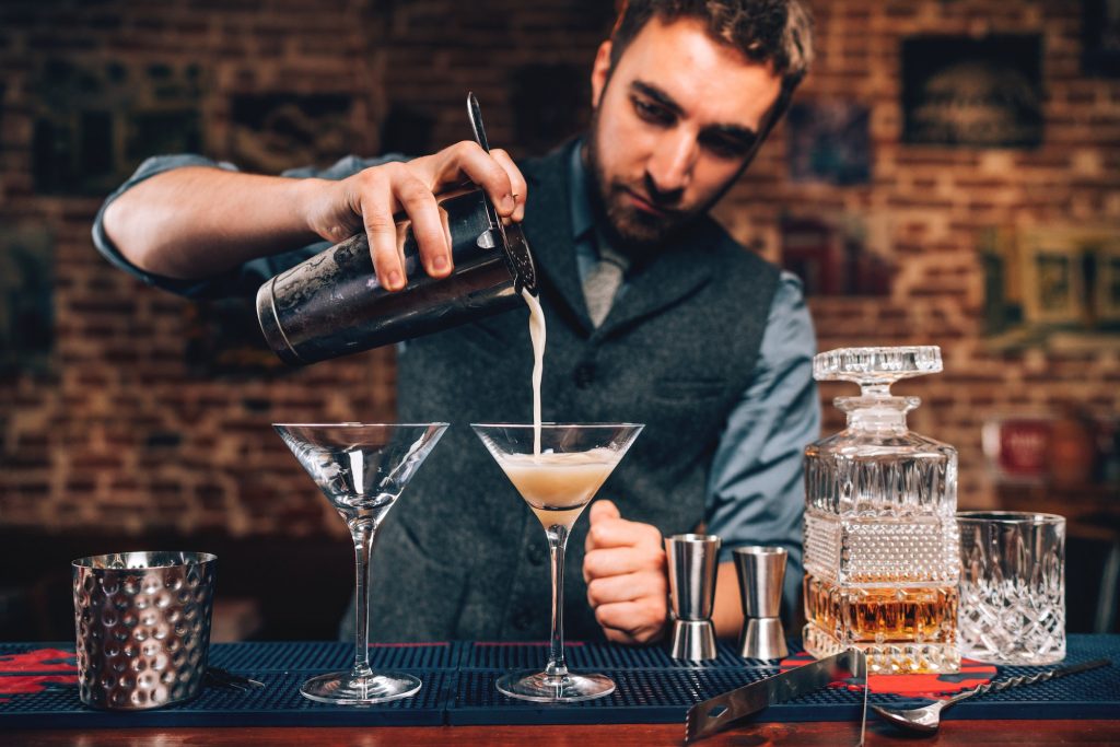 barman pouring fancy cocktail in bar at party. Manhattan cocktail beverage in nightclub