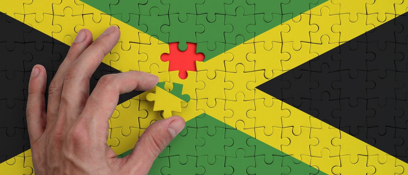 Jamaica flag is depicted on a puzzle, which the man's hand completes to fold.