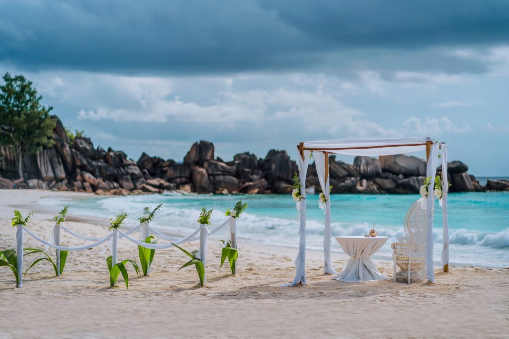 Beach wedding arch ceremonial decorated with white flowers on a tropical white sand beach. Paradise