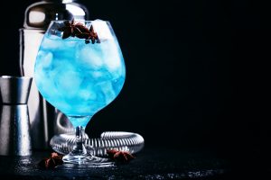 Blue cocktail with ice and anise in brandy glass