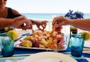 Family fun on beach vacation eating boiled seafood on deck overlooking beach landscape and ocean.