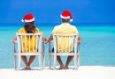 Young couple in Santa hats relaxing on beach during Christmas vacation