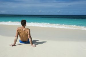 Caribbean, Anguilla, man sitting on the beach, rear view