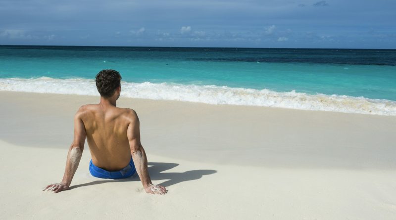 Caribbean, Anguilla, man sitting on the beach, rear view