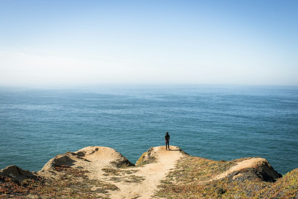 Man looking out over Pacific Ocean by Highway 1, California, USA