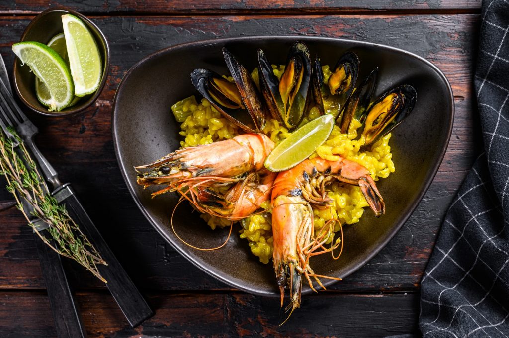 Seafood paella with prawns, shrimps, mussels. Black wooden background. Top view