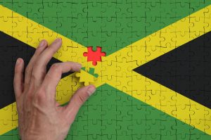 Jamaica flag is depicted on a puzzle, which the man's hand completes to fold.