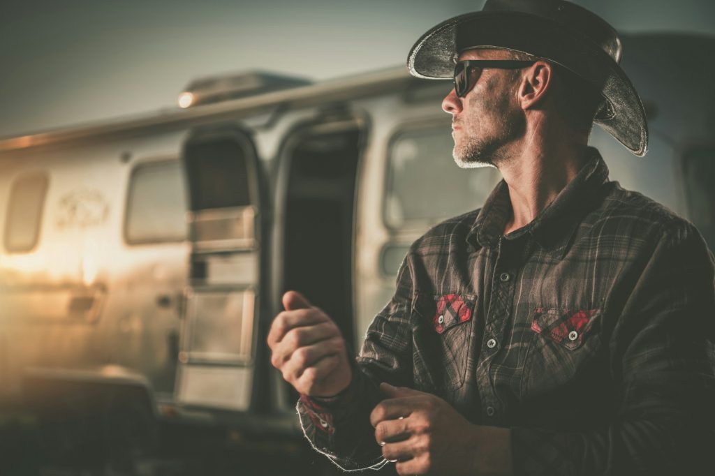 Portrait of American Cowboy Next to His Vintage Classic Travel Trailer