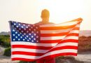 Rear vew of man holding USA American flag against sunset sky outdoor. Independence day of USA