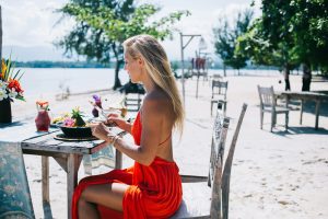 Satisfied young female eating exotic dish on beach