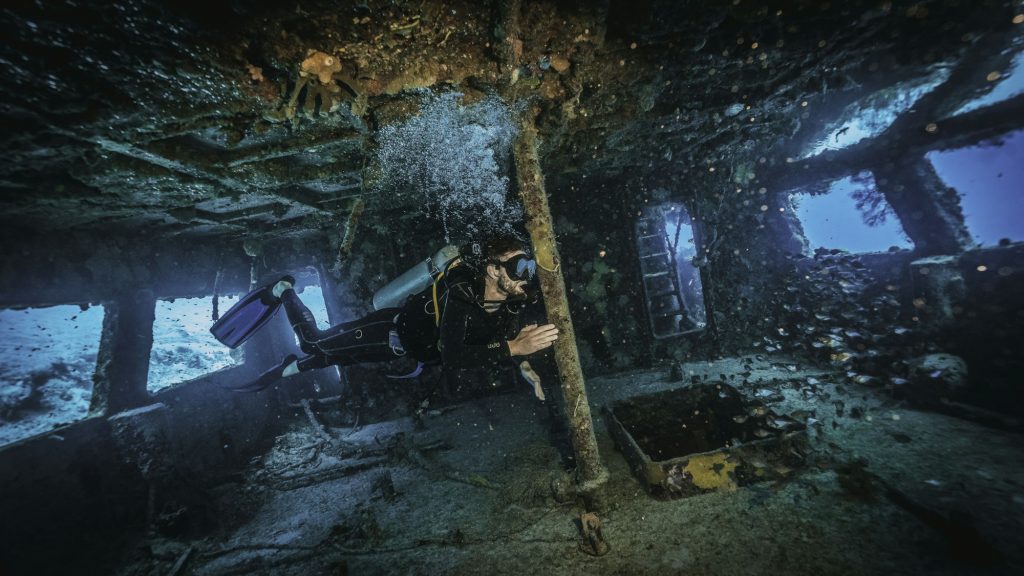 scuba diver exploring inside a military shipwreck