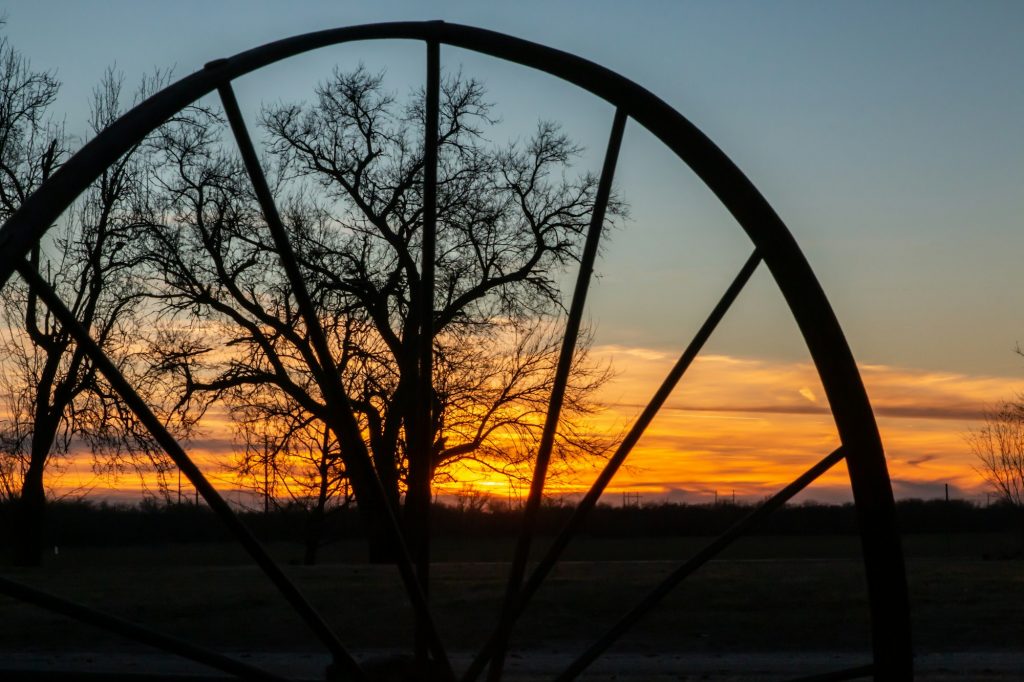 Sunset in rural kansas with trees silhouettes and wagon wheel
