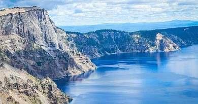 The cliffs and trees of Crater Lake National Park, Oregon. Blue sky and water.