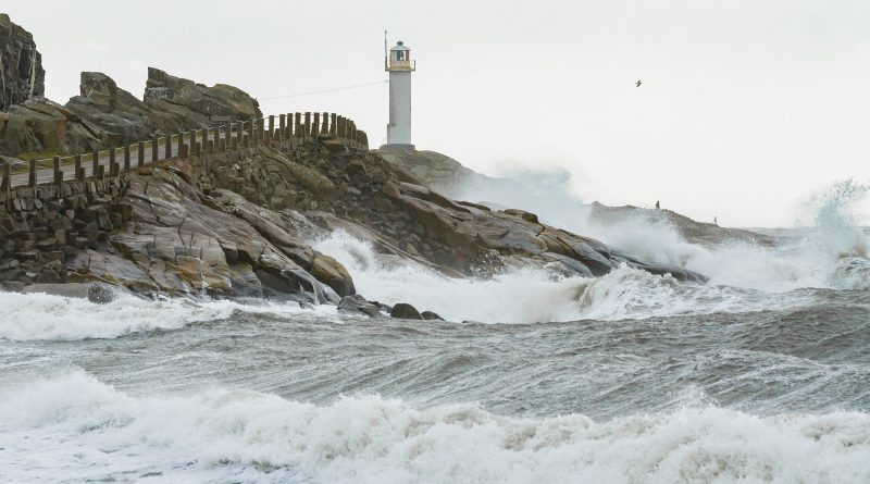 Storm Laura shows her muscles in hurricane stormy weather with lighthouse in background, big waves